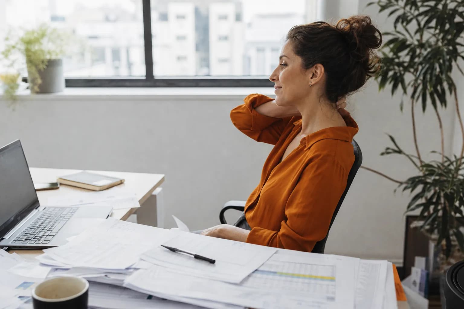 Medewerker leunt tevreden achterover na nauwkeurig werk aan een bureau vol spreadsheets