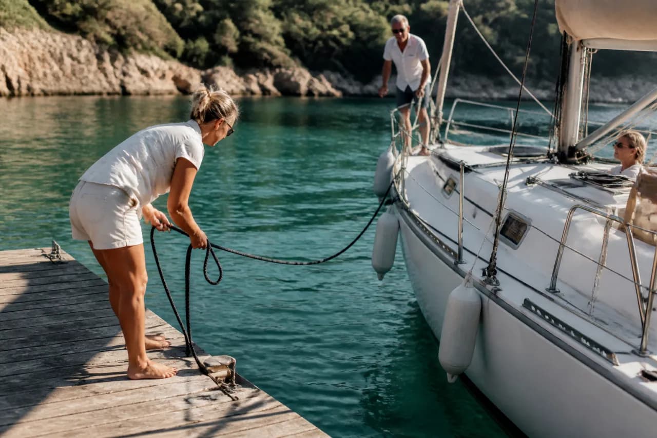 Zeilboot die aanmeert bij een houten steiger in een baai met turquoise water
