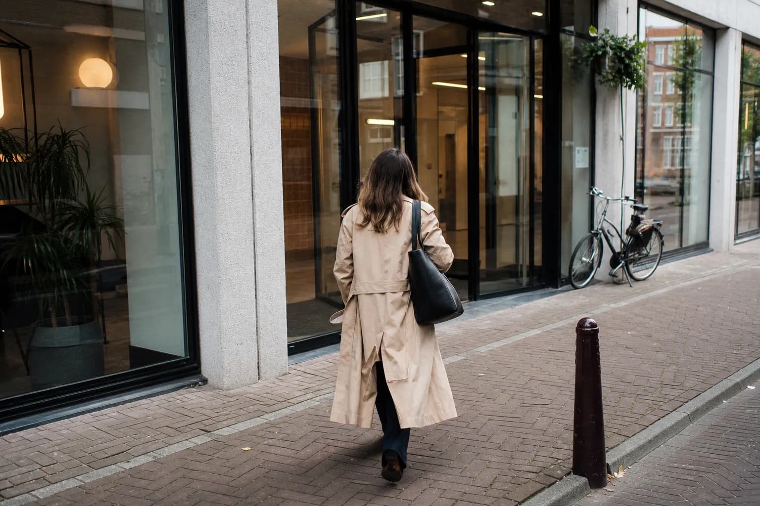 Iemand loopt op een Nederlandse straat naar de ingang van een kantoorgebouw