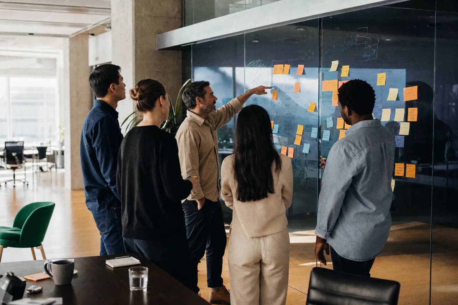 Team bij een glaswand vol post-its tijdens een strategieoverleg
